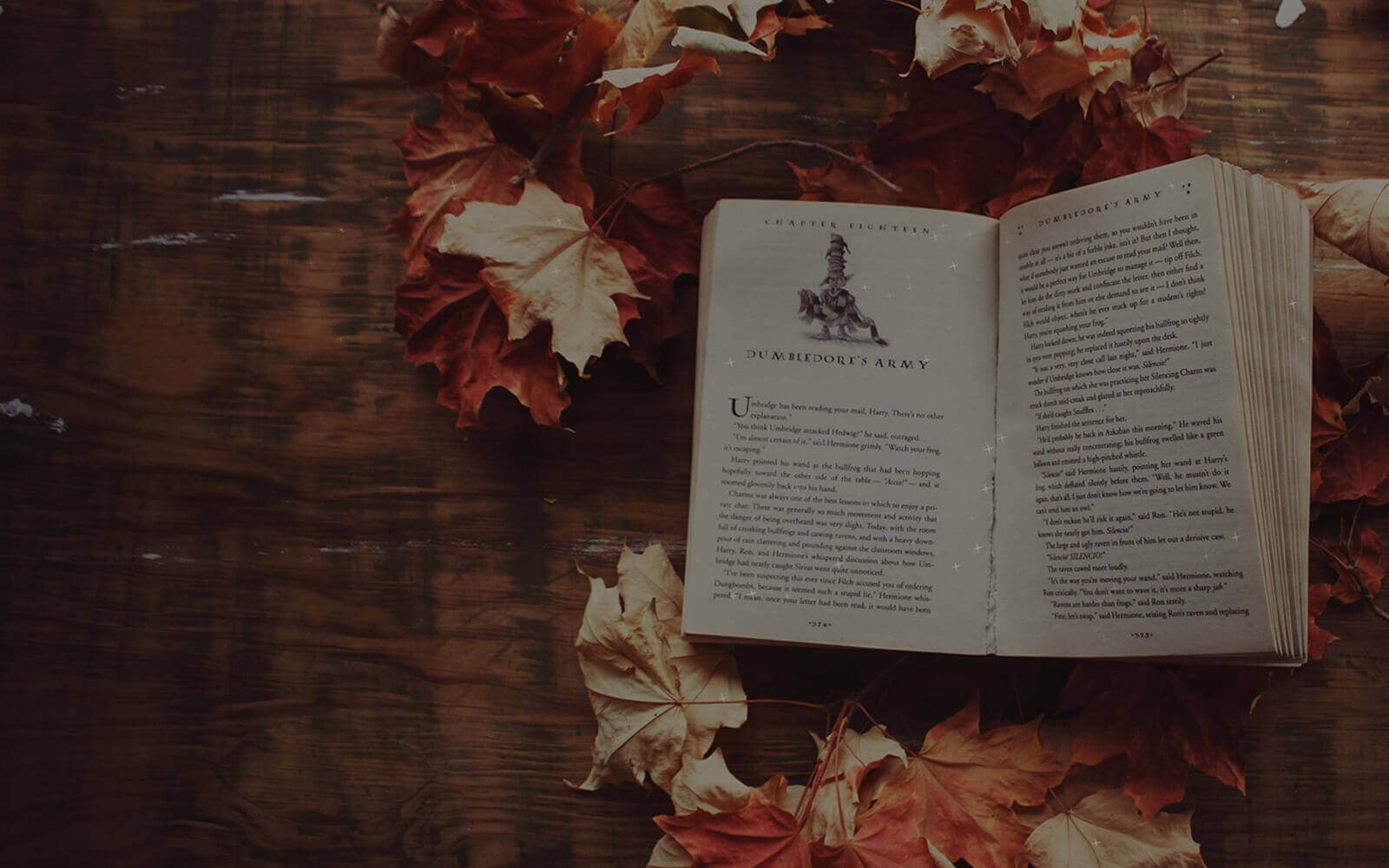 open harry potter book surrounded by orange and yellow autumn leaves on a brown desk