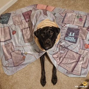 a black labrador wearing a blanket with a button made for readers